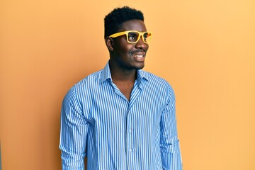 Fototapeta premium Handsome black man wearing yellow glasses looking to side, relax profile pose with natural face and confident smile.