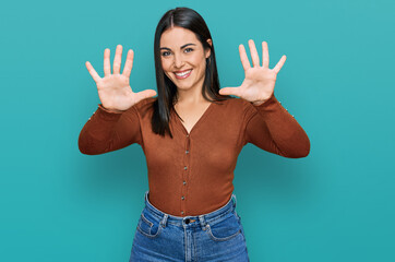 Young hispanic woman wearing casual clothes showing and pointing up with fingers number ten while smiling confident and happy.