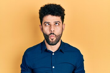 Young arab man with beard wearing casual shirt making fish face with lips, crazy and comical gesture. funny expression.