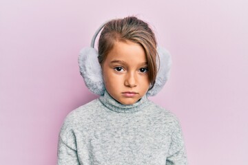 Little beautiful girl wearing fluffy earmuff relaxed with serious expression on face. simple and...