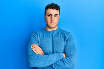 Hispanic young man wearing casual winter sweater skeptic and nervous, disapproving expression on face with crossed arms. negative person.