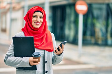 Fototapeta premium Young arab businesswoman using smartphone and drinking coffee at the city.
