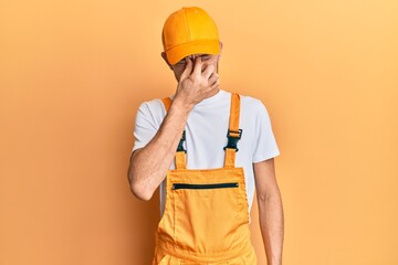 Hispanic young man wearing handyman uniform tired rubbing nose and eyes feeling fatigue and headache. stress and frustration concept.