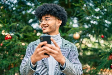 Fototapeta premium Young african american businessman smiling happy using smartphone at the park.