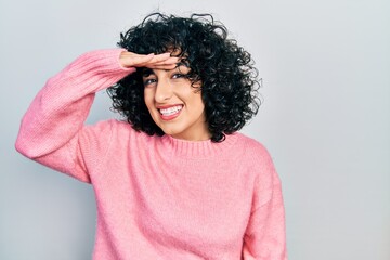 Young middle east woman wearing casual clothes very happy and smiling looking far away with hand...