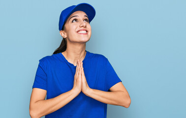 Young hispanic girl wearing delivery courier uniform begging and praying with hands together with hope expression on face very emotional and worried. begging.