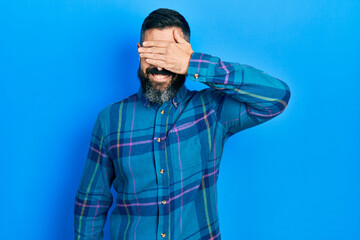 Young hispanic man wearing casual clothes smiling and laughing with hand on face covering eyes for surprise. blind concept.