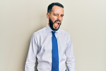 Young man with beard wearing business tie winking looking at the camera with sexy expression, cheerful and happy face.