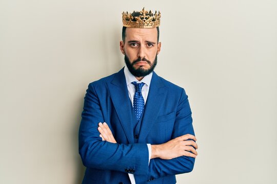 Young business man with beard wearing king crown depressed and worry for distress, crying angry and afraid. sad expression.