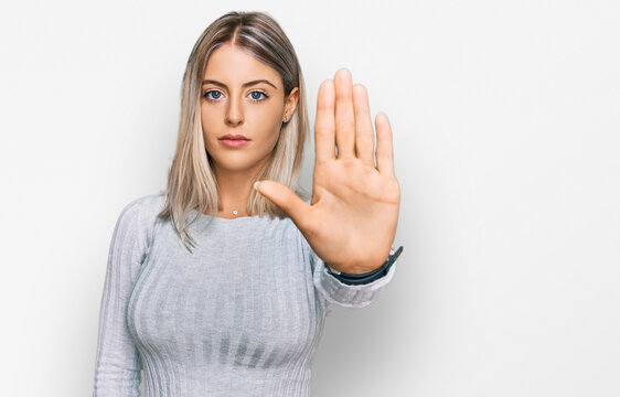 Beautiful blonde woman wearing casual clothes doing stop sing with palm of the hand. warning expression with negative and serious gesture on the face.