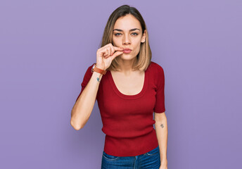 Young blonde girl wearing casual clothes mouth and lips shut as zip with fingers. secret and silent, taboo talking © Krakenimages.com