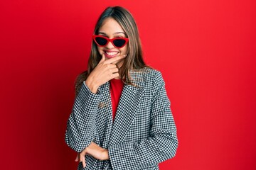 Fototapeta premium Young brunette woman wearing fashion and modern look looking confident at the camera smiling with crossed arms and hand raised on chin. thinking positive.