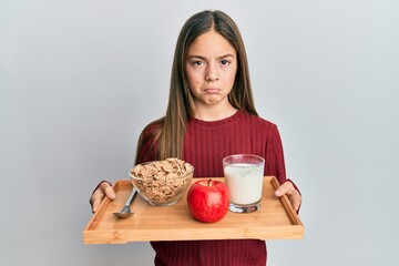 Beautiful brunette little girl holding tray with breakfast food depressed and worry for distress,...