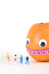 An anthropomorphic orange is wrapped around a soft ruler while watching a miniature figure running