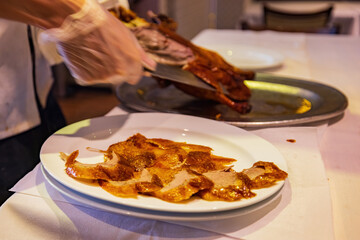 Close up shot of people slicing peking duck in to a plate