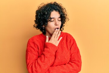 Fototapeta na wymiar Young hispanic woman with curly hair wearing casual winter sweater bored yawning tired covering mouth with hand. restless and sleepiness.