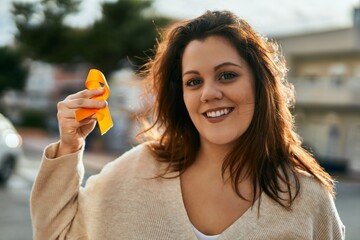 Young irish plus size girl smiling happy holding orange awareness ribbon at the city.