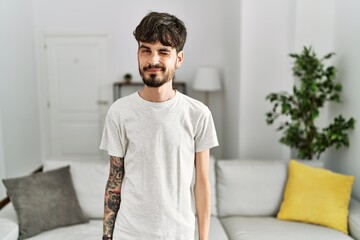 Hispanic man with beard at the living room at home winking looking at the camera with sexy...