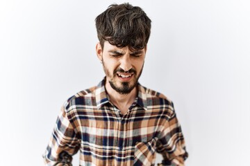 Hispanic man with beard standing over isolated background with hand on stomach because indigestion, painful illness feeling unwell. ache concept.