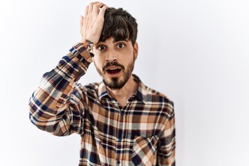 Obraz premium Hispanic man with beard standing over isolated background surprised with hand on head for mistake, remember error. forgot, bad memory concept.