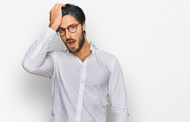 Young hispanic man wearing business shirt and glasses surprised with hand on head for mistake, remember error. forgot, bad memory concept.