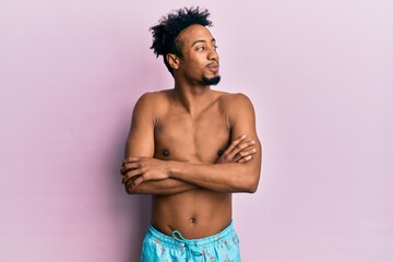 Fototapeta premium Young african american man with beard wearing swimsuit smiling looking to the side and staring away thinking.