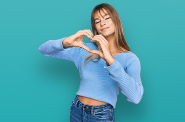 Teenager caucasian girl wearing casual clothes smiling in love doing heart symbol shape with hands. romantic concept.