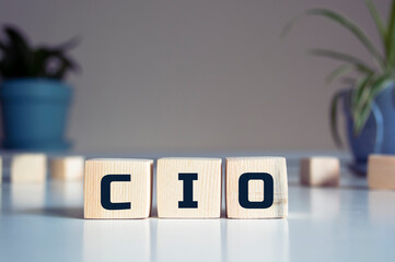 CIO written on wooden cubes - arranged in a vertical pyramid, grey and blur background, CIO - short for Chief Information Investment Officer, business concept - obrazy, fototapety, plakaty