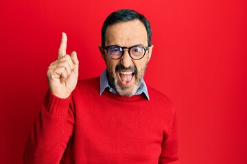Middle age hispanic man wearing casual clothes and glasses pointing finger up with successful idea. exited and happy. number one.