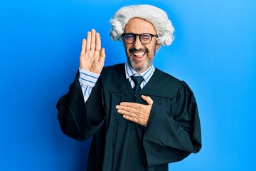 Middle age hispanic man using gavel winking looking at the camera with sexy expression, cheerful...