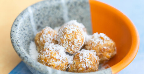 Closeup of the sweet and tasty mango flavored energy balls covered in shredded coconut in a bowl