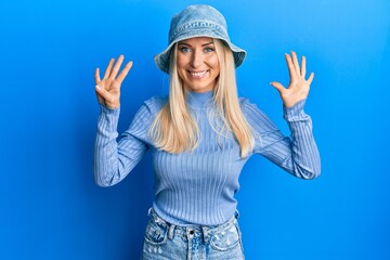 Obraz na płótnie Canvas Young blonde woman wearing casual denim hat showing and pointing up with fingers number nine while smiling confident and happy.