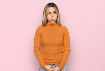 Young caucasian woman wearing casual clothes puffing cheeks with funny face. mouth inflated with...
