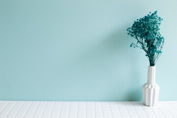 Vase of baby's breath, gypsophila dry flowers on white mosaic tile table. blue wall background. Home interior - obrazy, fototapety, plakaty