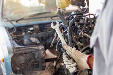 Fototapeta na wymiar Hand of car mechanic holding wrench, Automotive repair service in the workshop