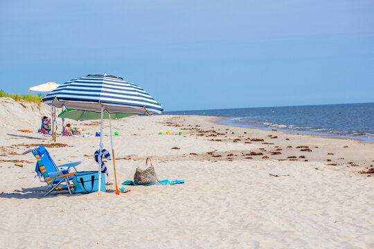 Blue skies and Sunny Days by the Seashore Sitting in the Sand Under the Blue Stripe Beach Umbrella