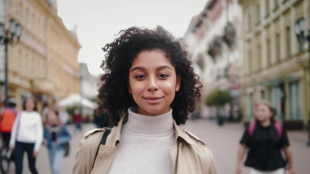 Portrait of a happy black african american woman smiling, tourist student, black fashion model smiling, curly afro hairstyle, generation z lifestyle, teenager walking