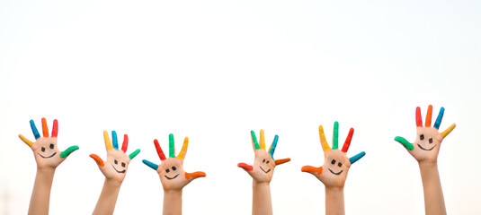 Banner view of children hands in colorful paint with funny smile face isolated on white background