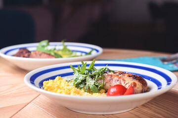 Risotto with pork sausages with cherry tomatoes and parsley on a plate. Italian cuisine concept