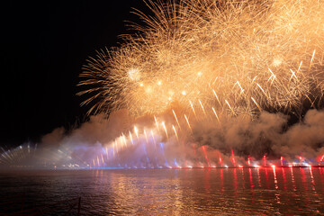 Festive colorful fireworks and illumination in dark sky with beautiful reflection in water. Holiday SCARLET SAILS