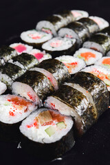 Mix of Japanese nori rolls in on a black background. Traditional Japanese sushi set over black.