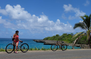 Fototapeta premium woman waiting on bicycle next to the coast in the caribbean sea