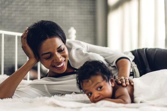 Portrait of enjoy happy love family african american mother playing with adorable little african american baby.Mom touching with cute son moments good time in a white bedroom.Love of black family