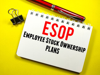 Business concept.Text ESOP (EMPLOYEE STOCK OWNERSHIP PLANS) on notebook with paper clips and pen on a yellow background.