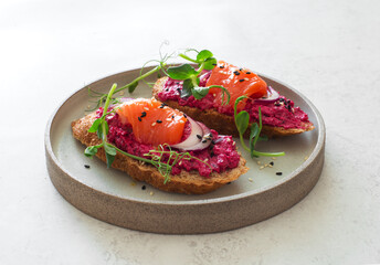 Open face sandwiches with beetroot hummus, salmon, sesame seeds and micro  greens close up