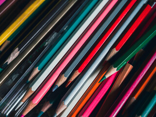 Colored pencils background. Close up various colors of old in used colored pencils on glass table in art studio, vintage tone style. Artist tools for making artworks.