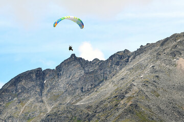 A paraglider flies through Alaska's Talkeetna Mountains on a sunny summer day.