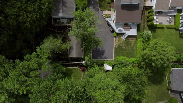 Overhead suburban neighborhood with push up over rooftops, trees, backyards, sidewalks, driveways and street.