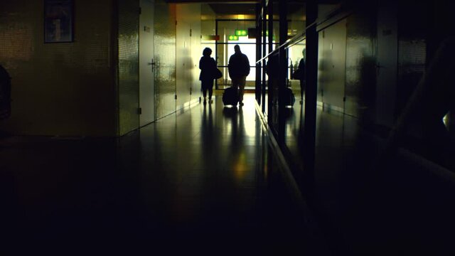 still view of two people couple of male and female woman and man walking down the hallway tunnel terminal gate in the airport with luggage in hand shot with black magic camera shot in vintage style