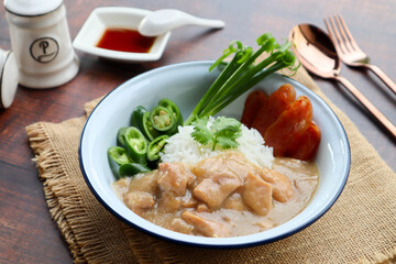 Chicken gravy over rice with sweet chili and Chinese sausage - Thai food called Khao Na Kai served on wood table